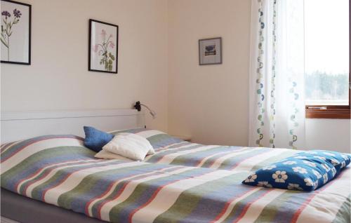 uma cama com um cobertor às riscas e duas almofadas em Stunning Home In Lckeby With Wifi em Ugglerum