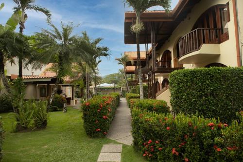 a courtyard of a house with flowers and plants at Apartotel Girasol in Jacó