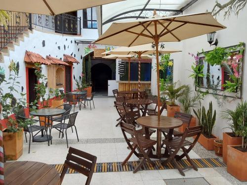 um pátio exterior com mesas, cadeiras e guarda-sóis em Hotel Cemandy by MA em Villa de Leyva