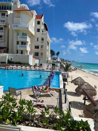 a resort swimming pool with people laying on the beach at capitan suites sea view in Cancún