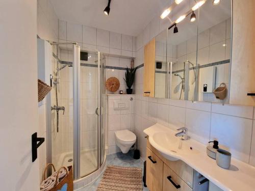 a bathroom with a shower and a sink and a toilet at Stylische Wohnung mit Weitblick und großem Balkon in Karolinenkoog