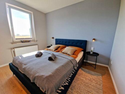 a bedroom with a large bed with a blue headboard at Stylische Wohnung mit Weitblick und großem Balkon in Karolinenkoog