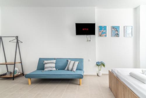 a blue couch in a white room with a tv at Brand New Studio near Downtown in Heraklio