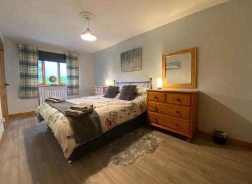 a bedroom with a bed and a dresser and a mirror at Sunningdale Lodge,St Mellion,Cornwall-FreeGolf&Spa in St. Mellion