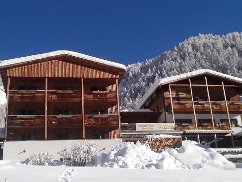 a building covered in snow with a mountain in the background at Hotel Edelweiss in Malles Venosta
