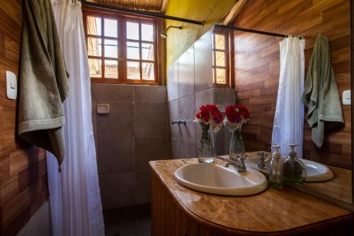 Baño con 2 lavabos y flores en una encimera en Inca Trail Glamping, en Cusco