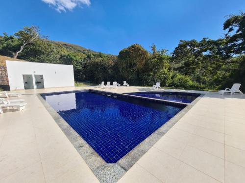 a swimming pool with blue water in front of a house at Casa Escarpas in Capitólio