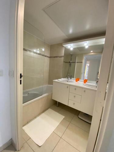 une salle de bain avec une baignoire, un lavabo et un miroir dans l'établissement Beau Rivage, à Cavalaire-sur-Mer