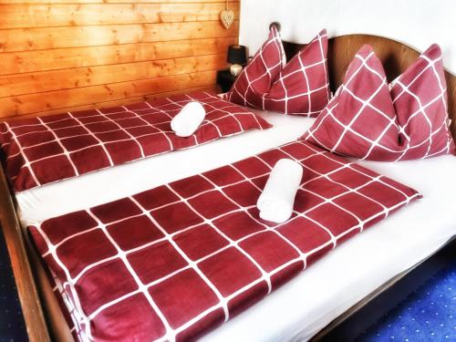 Cama con sábanas y almohadas rojas y blancas en das Bergerleben en Sonnenalpe Nassfeld