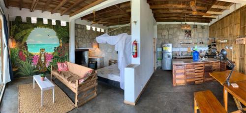 Punto Verde Ecological house في مونتانيتا: مطبخ وغرفة معيشة مع أريكة وطاولة