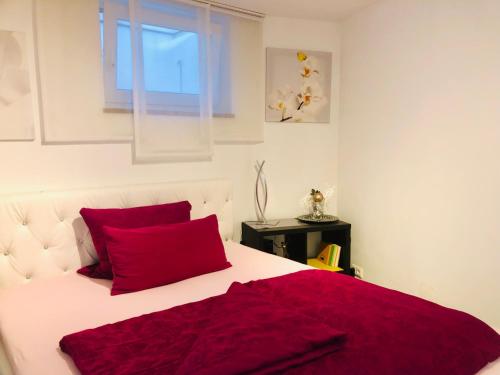 a white bed with red pillows and a window at nice Apartment in Schwarzenbruck