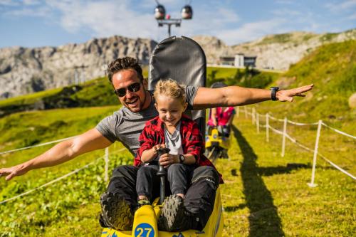 a man and a child riding on a roller coaster at das Bergerleben in Sonnenalpe Nassfeld