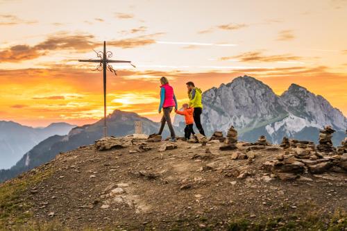 a family standing on top of a mountain with a cross at das Bergerleben in Sonnenalpe Nassfeld