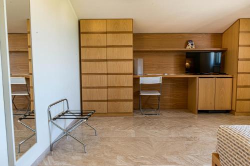 a room with a bed and a desk and a television at Hotel Poggio Bertino in Montemerano