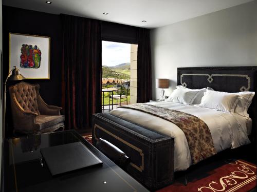 a bedroom with a bed and a table and a window at Hotel Castillo de Gorraiz&Spa in Gorraiz