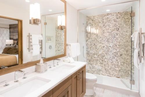 a bathroom with two sinks and a toilet and a shower at Luxury 1 Bedroom Downtown Aspen Vacation Rental With Access To A Heated Pool, Hot Tubs, Game Room And Spa in Aspen