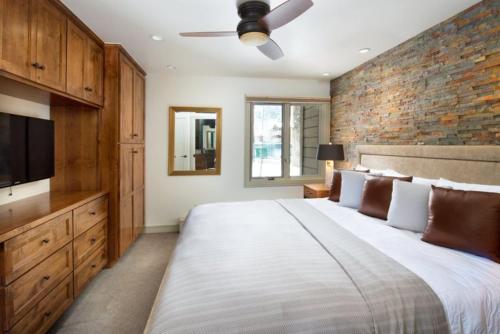 a bedroom with a large bed and a brick wall at Luxury 1 Bedroom Downtown Aspen Vacation Rental With Access To A Heated Pool, Hot Tubs, Game Room And Spa in Aspen