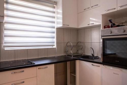 a kitchen with white cabinets and a sink and a window at Gazdinstvo Tadić in Nikšić