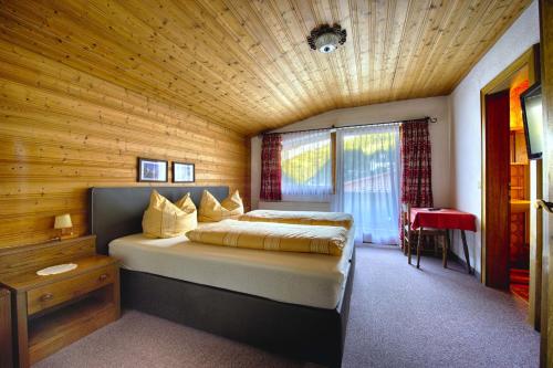 a bedroom with a bed and a wooden ceiling at Garni Fischer in Oetz