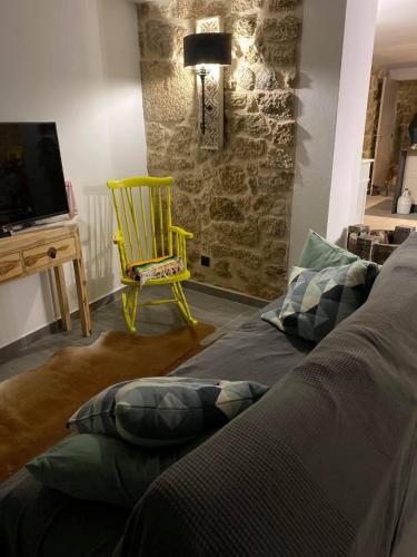 a living room with a bed and a yellow chair at Casa da Avó Maria in Monsanto