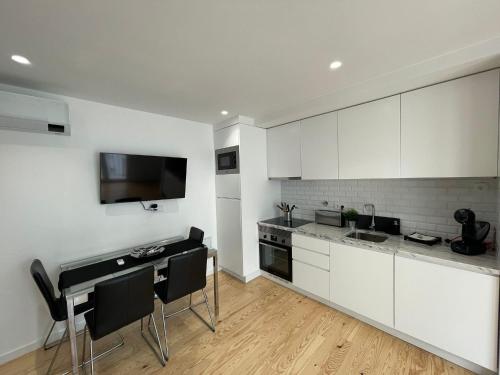 a kitchen with white cabinets and a table with black chairs at Lux Life Properties in Nazaré