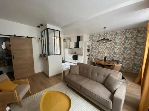 ein Wohnzimmer mit einem Sofa und einem Tisch in der Unterkunft L'Ilot du Perche: Appartement cosy avec jardin in Bellême