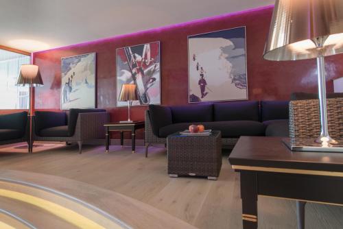 a lobby with a couch and chairs and paintings at Hotel Zürserhof in Zürs am Arlberg