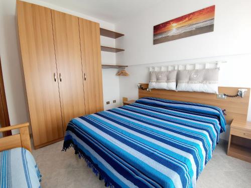 a bedroom with a bed with a blue striped blanket at VILLA ROSSINI in Valledoria