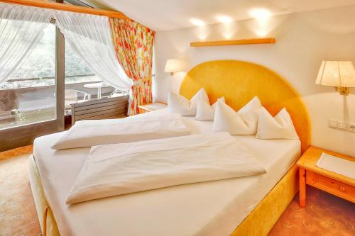 a bedroom with two beds and a large window at Hotel Pfeifer in Gaschurn