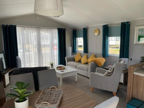 ein Wohnzimmer mit einem Sofa, Stühlen und einem Tisch in der Unterkunft 6 Berth Comfy Homely Caravan, Dog Friendly in Belton