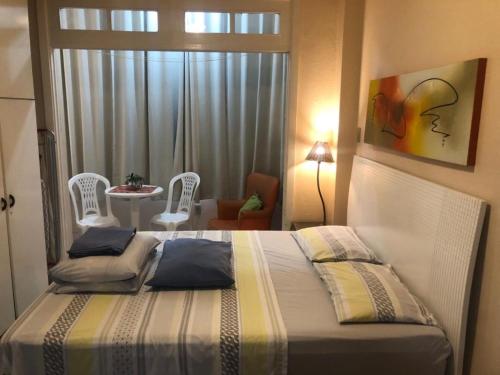 1 dormitorio con 1 cama, mesa y sillas en Meio de Copacabana, 200 metros da praia, posto 5, en Río de Janeiro