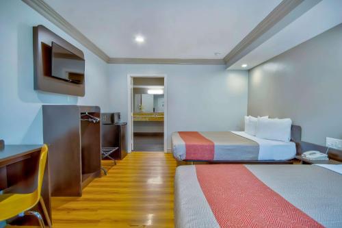 a hotel room with two beds and a desk at Motel 6 Gardena in Gardena