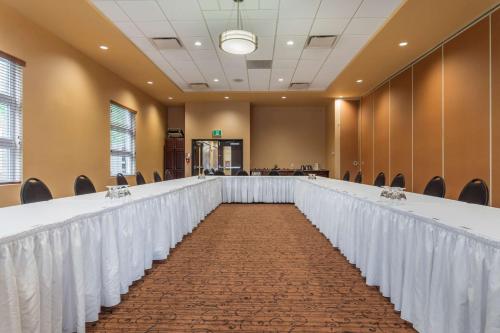 a long table with white curtains and chairs in a room at Best Western Plus, Bathurst Hotel & Suites in Bathurst