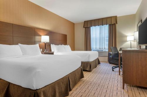 バサーストにあるBest Western Plus, Bathurst Hotel & Suitesのベッド2台とデスクが備わるホテルルームです。