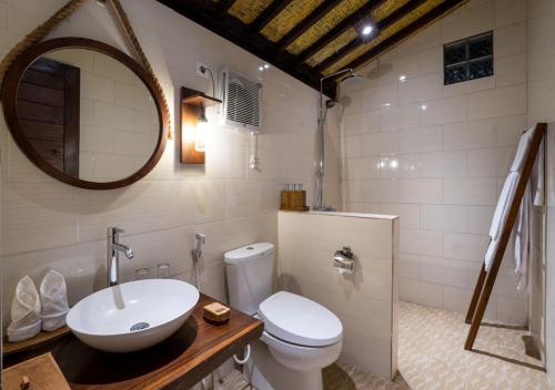 a bathroom with a sink and a toilet and a mirror at Amanuba Ersadeva Resort in Pulukan