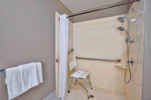 a bathroom with a shower and a stool in it at Motel 6 Tulsa, Ok - Central in Tulsa