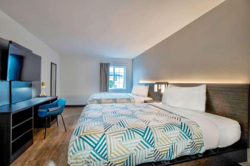 a hotel room with two beds and a television at Motel 6 Tulsa, Ok - Central in Tulsa
