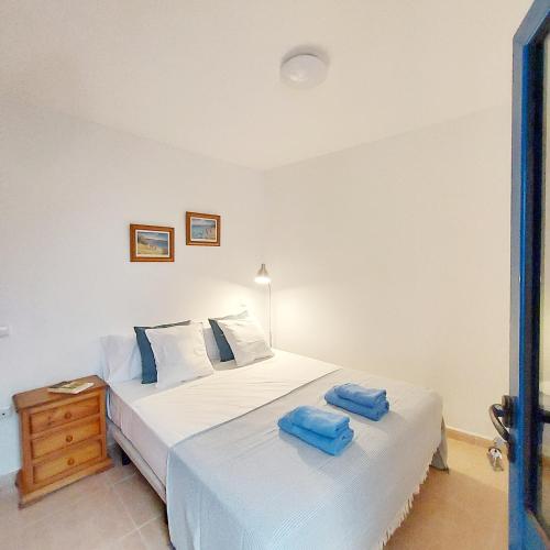 two beds in a bedroom with two blue towels on them at Cotillo Ocean in El Cotillo