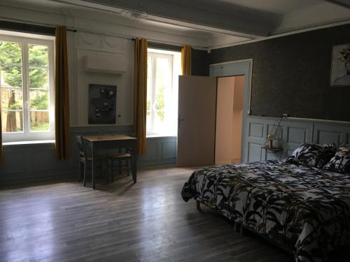 a bedroom with a bed and a table and windows at Le mas Rocamour in Roquemaure