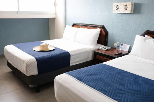 a hotel room with two beds with a hat on top at Hotel Los Aluxes in Mérida