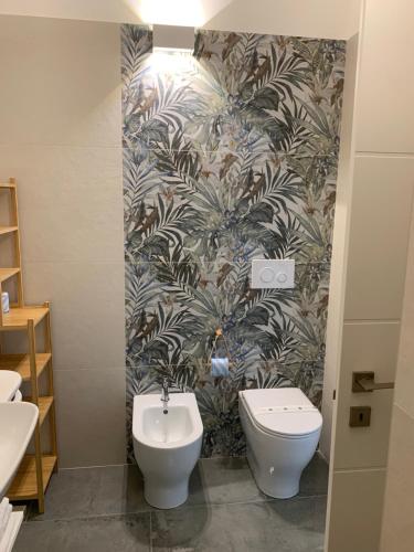 a bathroom with a toilet and a plant wallpaper at San Pietro Home in San Pietro in Bevagna
