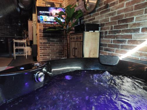 a bathtub filled with purple water next to a brick wall at La cachette sous les toits balnéo climatisé in Nantes