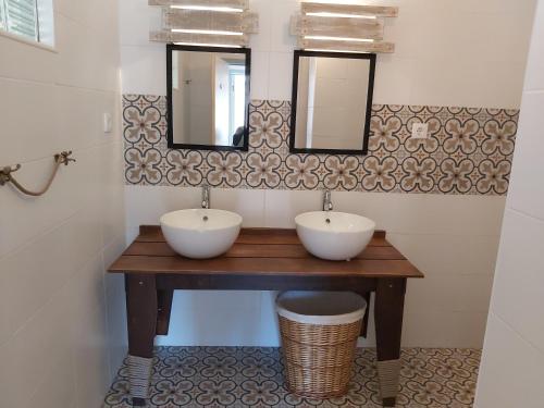 a bathroom with two sinks and two mirrors at O Refúgio in Coimbra