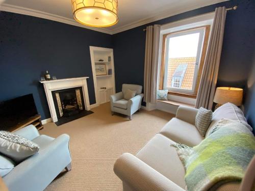 a living room with a white couch and a fireplace at Coastal Retreat in Fife