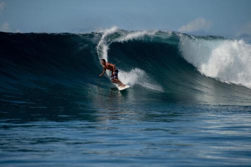 a man riding a wave on a surfboard in the ocean at Maqai Beach Eco Resort in Qamea