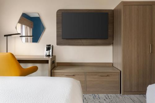 a bedroom with a bed and a tv on a wall at Holiday Inn Express & Suites Greenville-Downtown by IHG in Greenville
