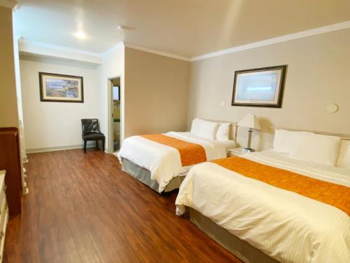 una habitación de hotel con 2 camas y una silla en Monarch Valley Inn Marina at Monterey Bay en Marina
