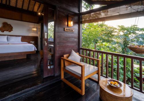 a room with a bed and a chair on a balcony at Amanuba Ersadeva Resort in Pulukan