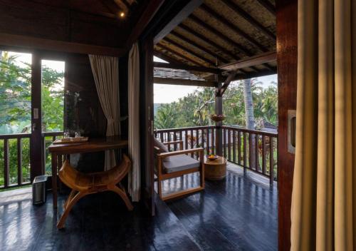 a porch with a table and a chair on a balcony at Amanuba Ersadeva Resort in Pulukan