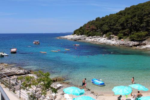 a group of people on a beach with blue umbrellas at Apartments by the sea Mali Losinj, Losinj - 19959 in Mali Lošinj